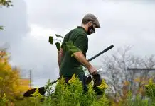 a man in a green shirt holding a pair of gardening tools